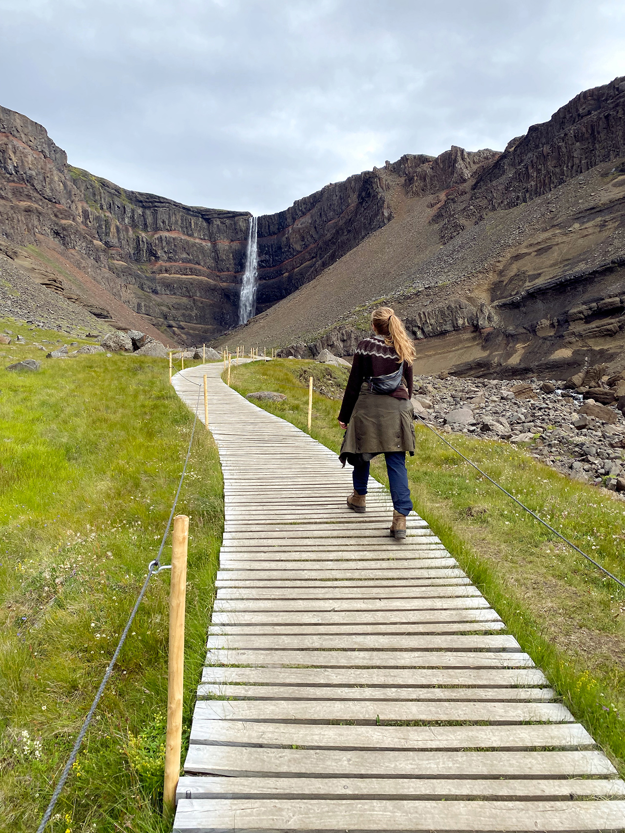Woman hiking to Hengifoss waterfall